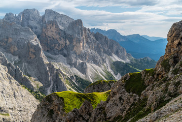 Landscape of Dolomites with green meadows, blue sky, white clouds and rocky mountains.  Italian Dolomites landscape.  Beauty of nature concept background.  The valley below.  Evening panoramic view.  