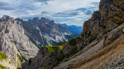 Fototapeta na wymiar Landscape of Dolomites with green meadows, blue sky, white clouds and rocky mountains. Italian Dolomites landscape. Beauty of nature concept background. The valley below. Evening panoramic view. 