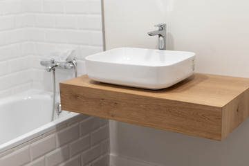 Fototapeta na wymiar White modern bathroom sink on a huge wood table
