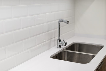 Modern chrome sink and faucet on a design white kitchen