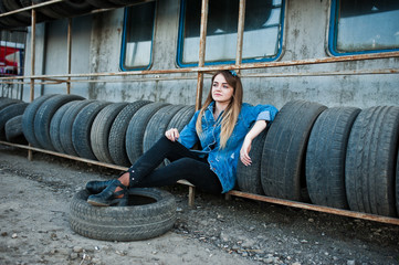 Young hipster girl in jeans jacket and head scarf at tire fitting zone.