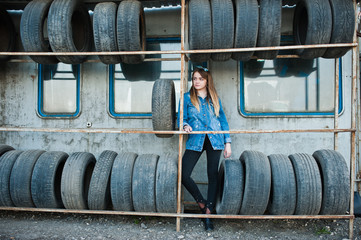 Young hipster girl in jeans jacket and head scarf at tire fitting zone.
