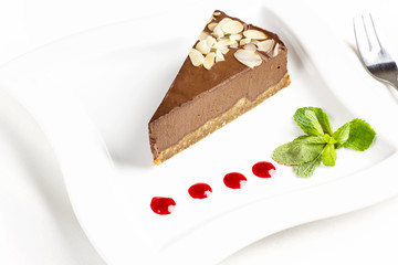 The piece of chocolate souffle cake with mint and jam drops on white plate