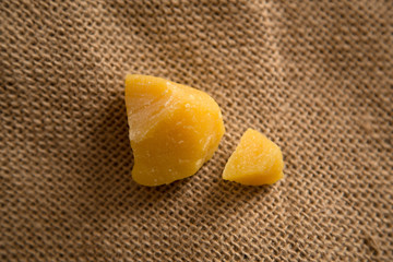 Pieces of natural bees wax on neutral jute background. Blocks of yellow wax.