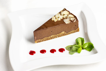 The piece of chocolate souffle cake with mint and jam drops on white plate