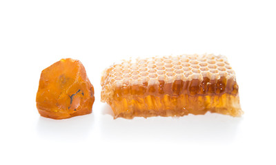 Pieces of honeycomb and natural amber stone. Fresh bee honey pieces colour on white background compared with colour of amber.