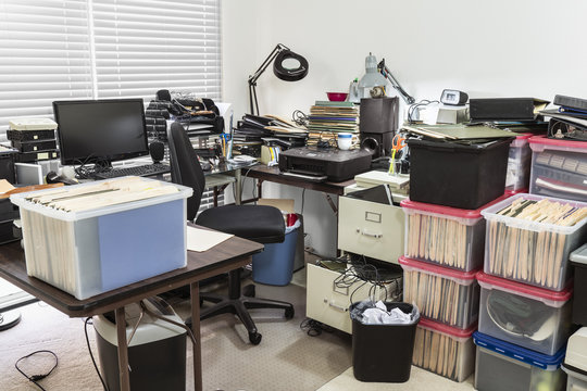 Messy business office with cluttered desk and boxes full of files.