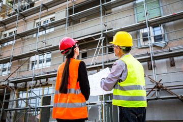 Engineers and worker discuss front of building