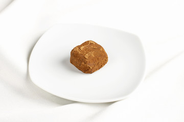 Handmade raw food candy truffle in cocoa on white platter