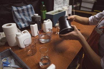 Female photographer cleaning a lens cover with liquid