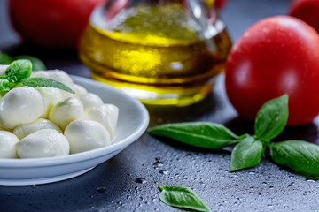 Mozzarella, red tomatoes and fresh Basil on a black background. top view. Flat lay. Food concept. Healthy and wholesome food
