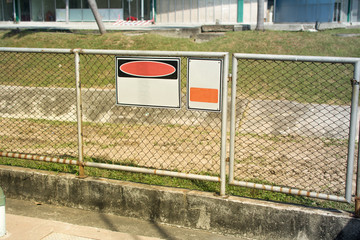 Empty blank white label hanging on mesh fence.