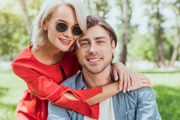 Fototapeta premium portrait of smiling couple hugging in park and looking at camera