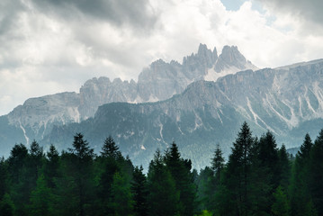Landscape of Dolomites with green meadows, blue sky, white clouds and rocky mountains. Italian Dolomites landscape. Beauty of nature concept background. The valley below. Evening panoramic view. 