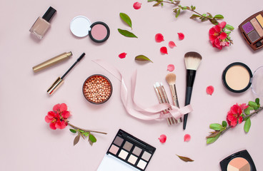Obraz na płótnie Canvas Various cosmetic products for make-up with red flowers on a pink background. Makeup Accessories Top view Flat Lay. Powder Rouge Eyeshadow Corrector Brushes Mascara