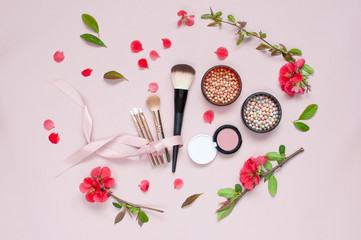 Obraz na płótnie Canvas Various cosmetic products for make-up with red flowers on a pink background with copy space. Makeup Accessories Top view Flat Lay. Powder Rouge Eyeshadow Corrector Brushes Mascara