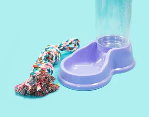 Gordijnen Pet accessories concept.  Water feeder with rope on blue background. © Suphansa