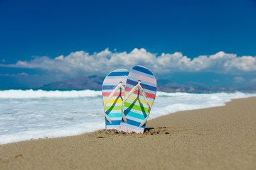 Colored sandals stuck in the sand on the beach of Tympaki, Crete, Greece