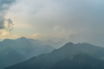 Italian Dolomites Landscape. Light after rain in Dolomites. Rocky peaks in the background surrounded by rain clouds. Mountain valley with layers of forest and mountains. Beautiful light in Alps. Italy