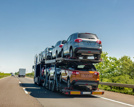 Car carrier trailer with new cars on bunk platform. Car transport truck on the highway