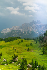 Landscape of Dolomites with green meadows, blue sky, white clouds and rocky mountains. Italian Dolomites landscape. Beauty of nature concept background. The valley below. Evening panoramic view. 