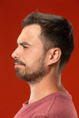 Obraz premium The young emotional angry man screaming on red studio background