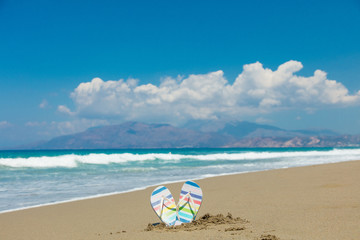 Fototapeta na wymiar Colored sandals stuck in the sand on the beach of Tympaki, Crete, Greece