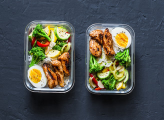 Rice, stewed vegetables, egg, teriyaki chicken - healthy balanced lunch box on a dark background,...