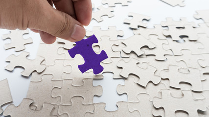 Fototapeta premium Hand put missing jigsaw puzzle into the paper board