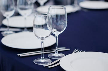 Tableware and silverware with glasses arranged on tablecloth for restaurant banquet