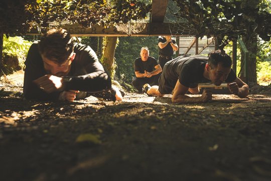 Fit mens crawling under the net during obstacle course