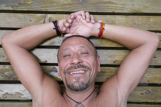Man lying on a wooden pallet after a sauna. People and lifestyle concept. Happy middle-aged man outdoor