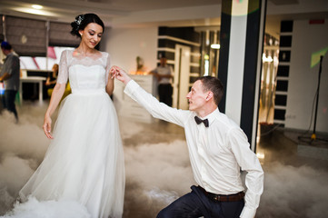 Fototapeta premium Romantic newly married couple performing their first dance in the restaurant with heavy smoke.