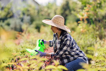Young female gardener watering the plants in garden
