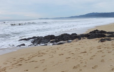 Blue landscape with sand and rocks on beach with waves 