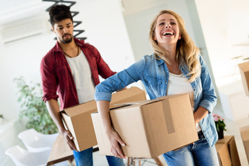 Young couple unpacking cardboard boxes at new home moving in concept