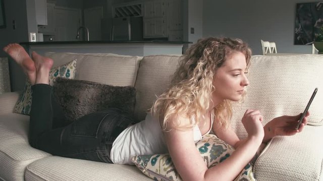 Cute blonde woman having video call with a friend in a modern home interior