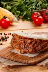 Arepa with seasoned mashed meat and some ingredients of its preparation around