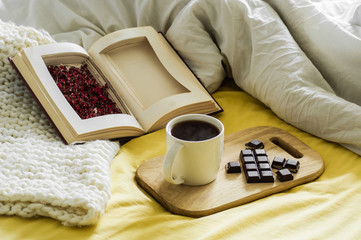 Spring Autumn still life. Breakfast in bed. White bedroom. Sweet home. Books, flowers, chocolate and coffee cup. flat lay
