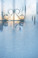 Fototapeta premium Frozen window with carved lattice slightly thawed from morning sun.