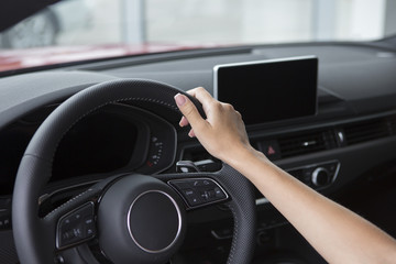 The hand of a girl with a stylish manicure lies on the handlebars in a saloon car.