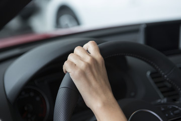 Naklejka premium The hand of a girl with a stylish manicure lies on the handlebars in a saloon car.
