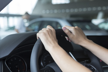 The hand of a girl with a stylish manicure lies on the handlebars in a saloon car.