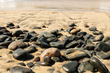 Fototapeta na wymiar Maspalomas, Canarias islands/ Spain-July 22, 2018: Gray stones on sand from Sahara desert and distance view of blue Atlantic ocean and beach on Canarias island, Gran Canaria.