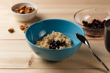 Porridge in a bowl with the berries, walnuts and cocoa on bright wooden table. Healthy breakfast image. Copy space
