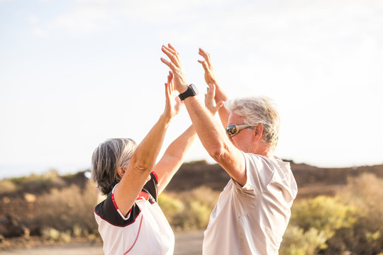 senior mature couple enjoy and win together giving five and hugging under a nice weather day of sun in summer. sport activity and clothes. Active aged people and happiness concept