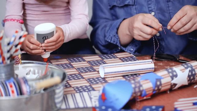 Step by step. Mother and daughter making paper firecrackers for July 4th celebration