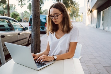 young beautiful girl working at a laptop on a laptop and drinking coffee