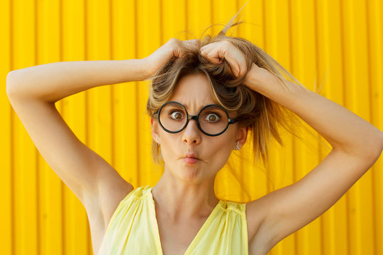 Portrait of a joyful girl wearing toy funny glasses looking up over yellow background