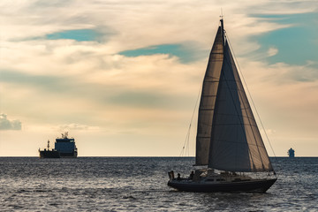 Blue sailboat against cargo ship